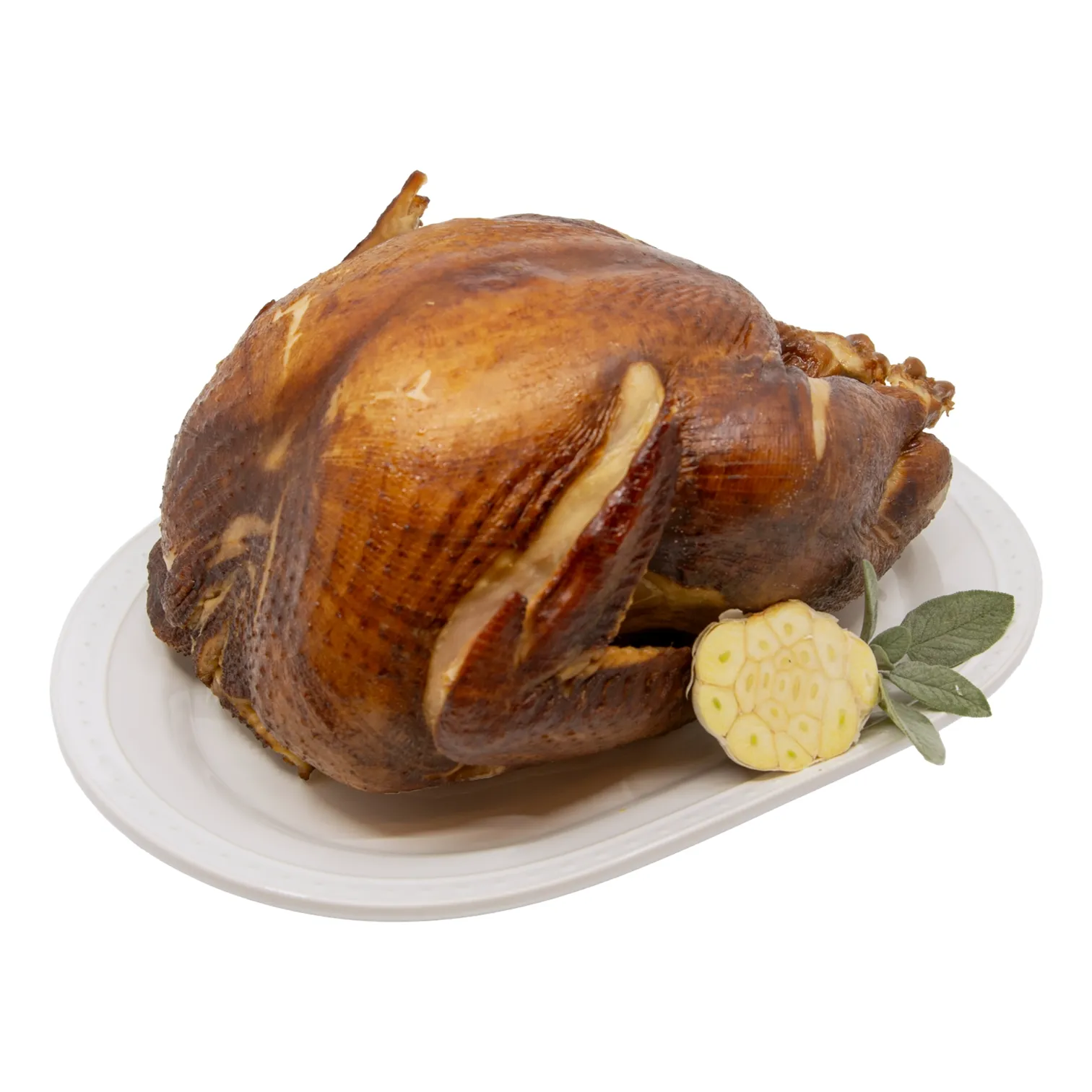 A whole golden-brown pecan smoked turkey rests on a white platter, garnished with sliced garlic and green leaves; a warm, festive meal.