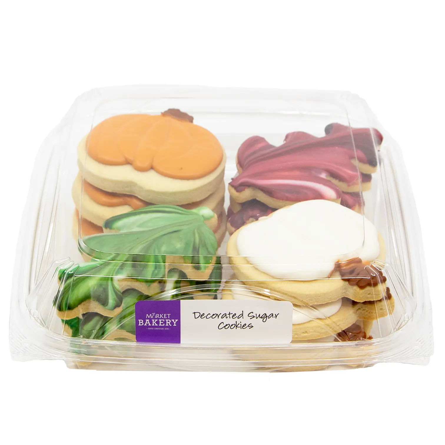 A clear plastic package holds colorful decorated sugar cookies shaped like fruit, leaves, and swirls. A Market Bakery label sits on the front.