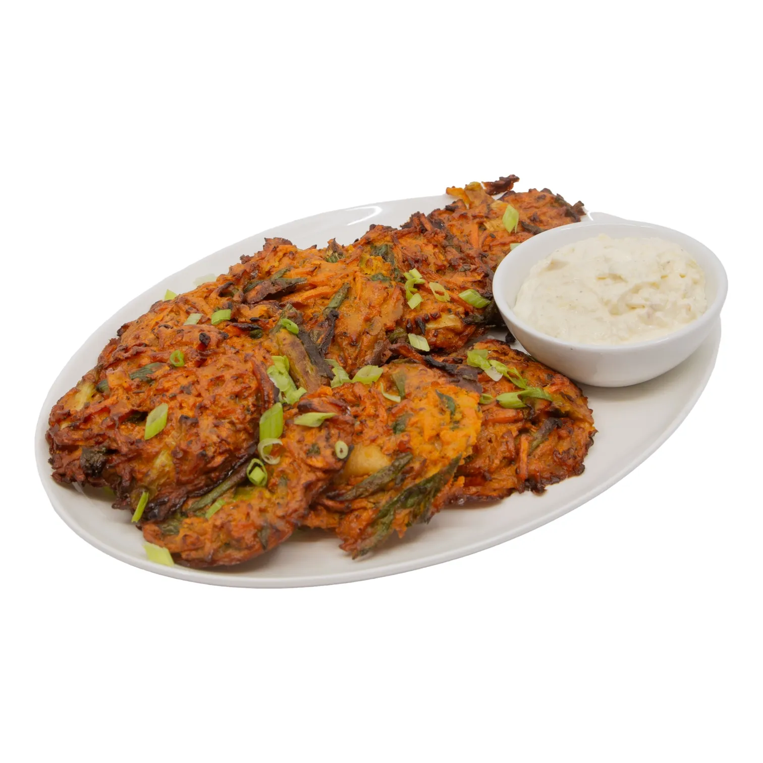 A platter of golden, sweet potato fritters topped with chopped green herbs, served with creamy white dipping sauce; appetizing and richly textured.