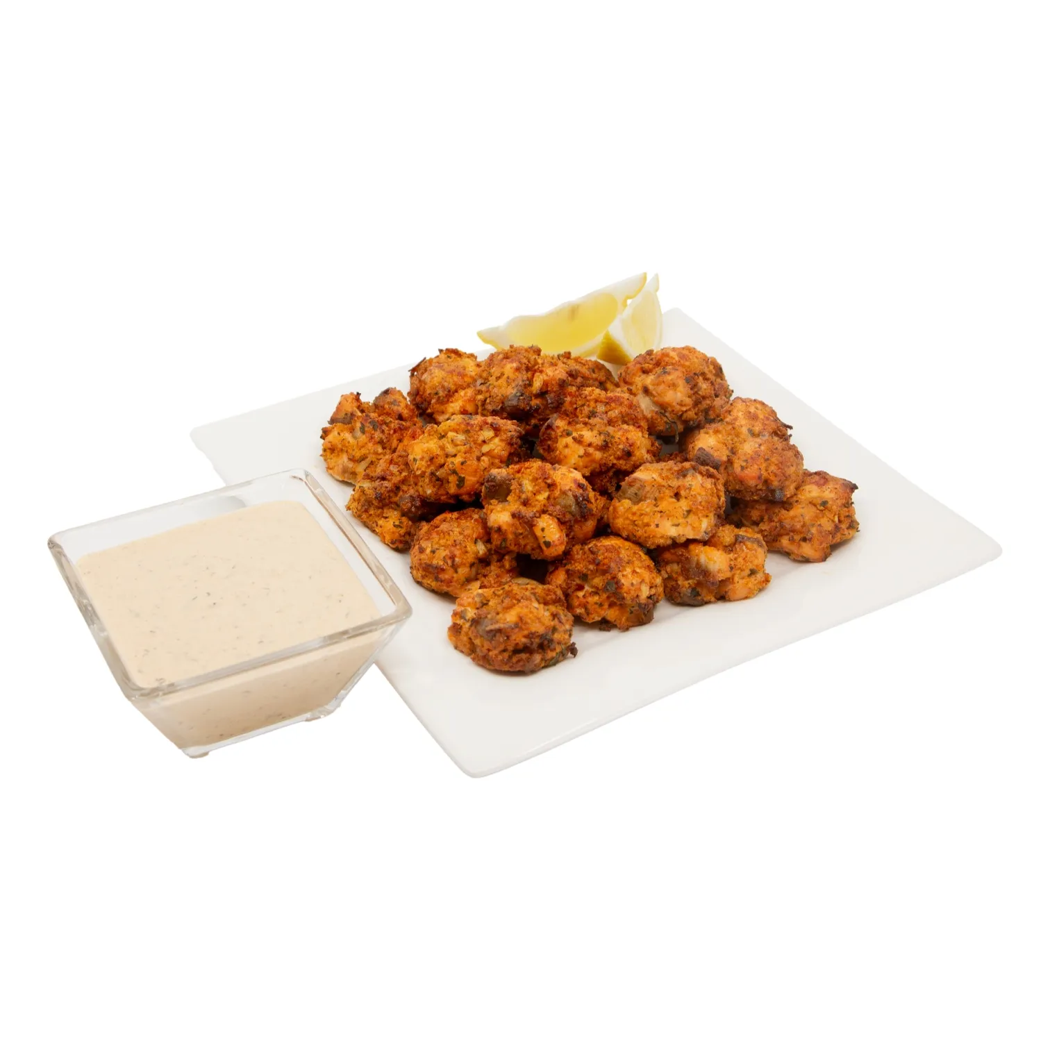 Golden, crispy blackened salmon cakes piled on a white platter with lemon wedges and creamy remoulade dipping sauce.