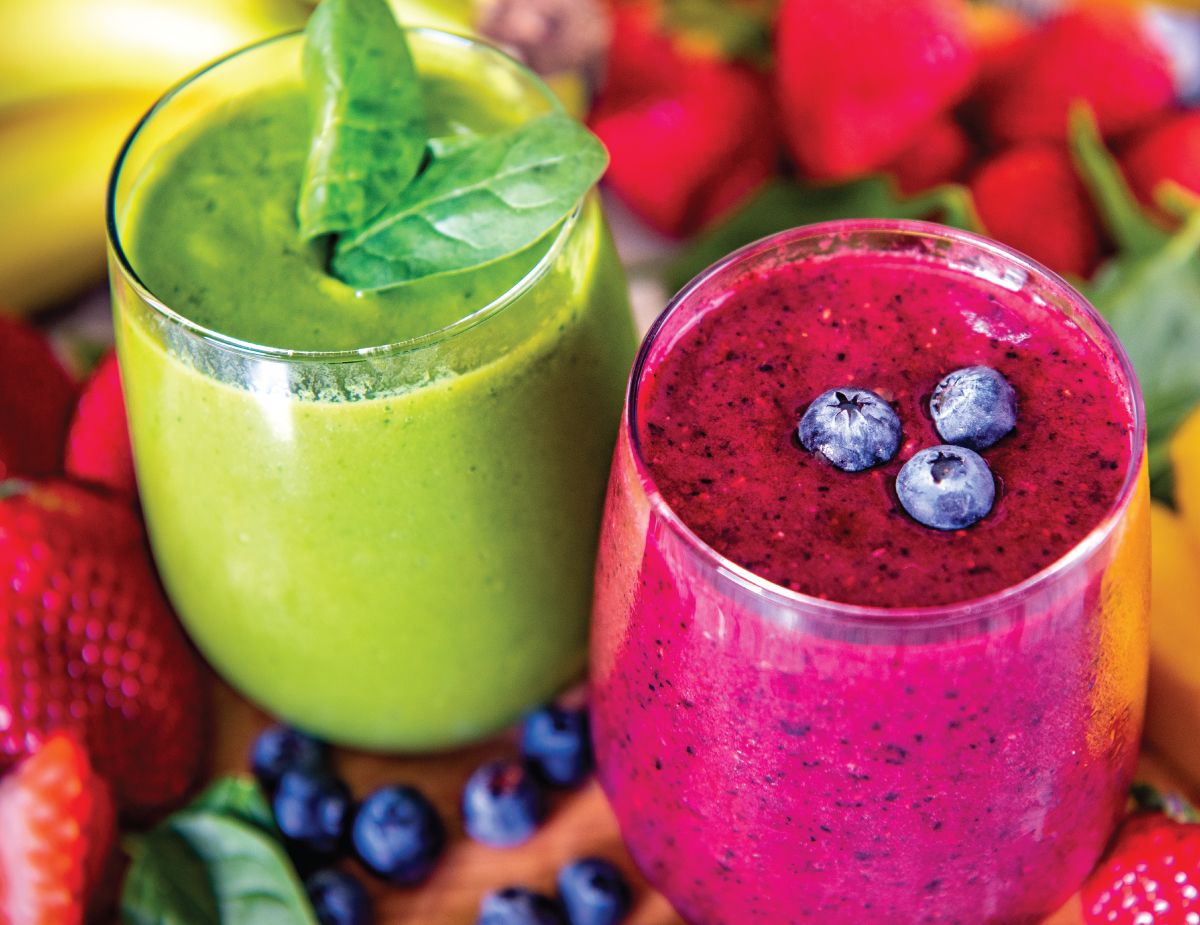 Vibrant smoothies in glasses with fresh fruits and veggies.