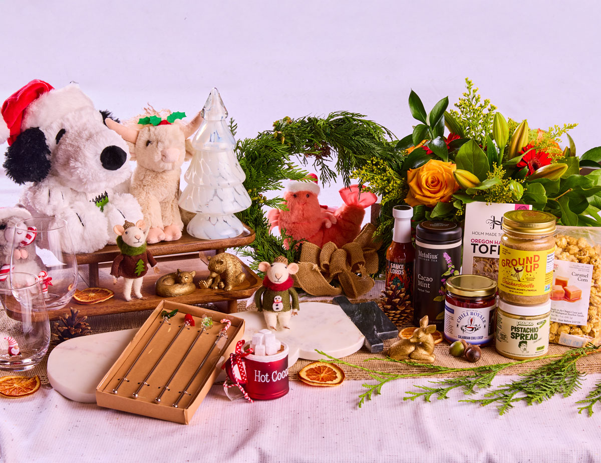 Oregon made products on a festive table display, including plushies, stemware, mugs, candle holders, fresh wreaths, flowers, tea, hot sauce, toffee, caramel corn and nut butters.