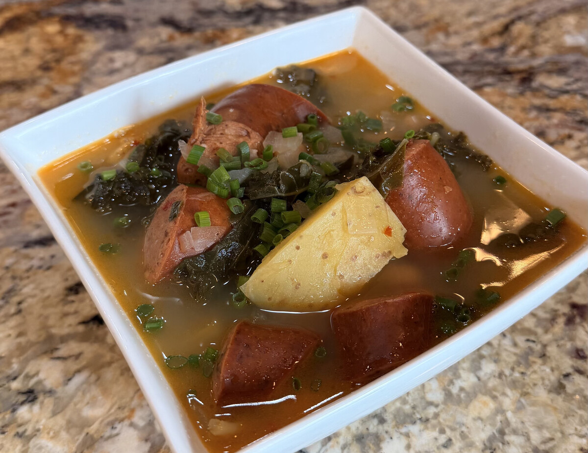 Bowl of Caldo Verde Portuguese soup with linguica sausage, kale, potatoes, and chives